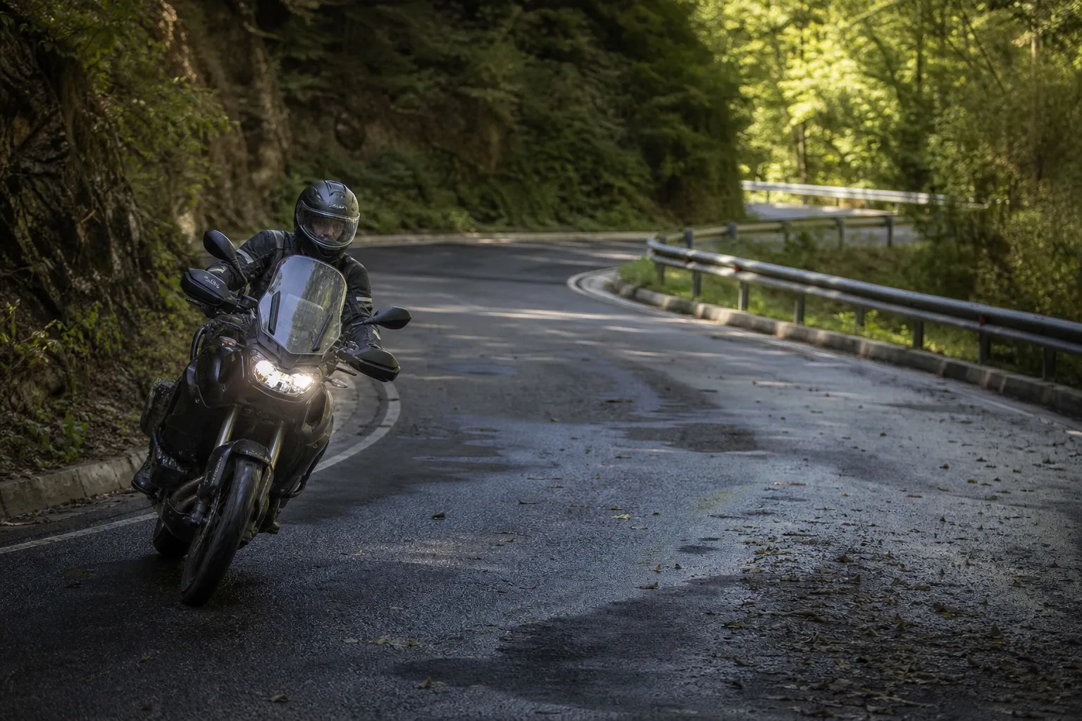 Motosikletlinin gölgeli ve kaygan olabilecek bir viraja kontrollü biçimde yaklaşması
